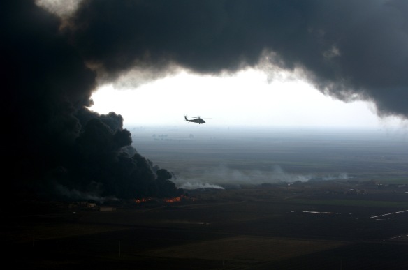 A plume of smoke surrounds a U.S. Army UH-60 Black Hawk helicopter as soldiers of the 101st Airborne Division conduct an aerial assessment of an oil pipeline fire outside Forward Operating Base McHenry, Iraq, on Dec. 27, 2005.  Elements of the 101st Airborne Division are deployed to Iraq from Fort Campbell, Ky.  DoD photo by Spc. Timothy Kingston, U.S. Army.  (Released)